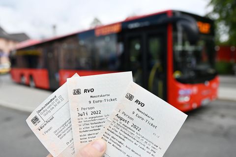 Eine Frau hält drei 9-Euro-Tickets für die Monate Juni, Juli und August vor einem Bus des PNV hoch