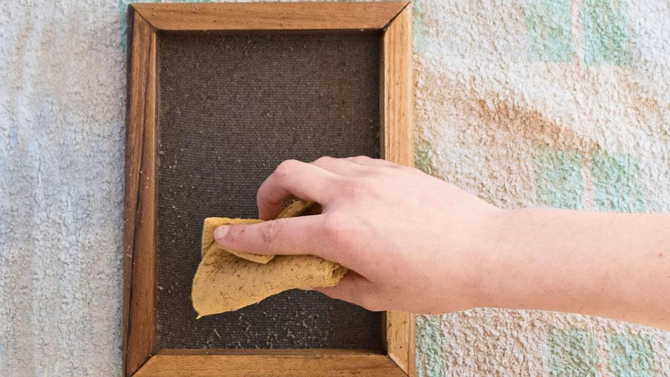 Ein Schöpfrahmen mit nassem Papier wird mit einem Schwamm abgetupft.