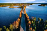 Luftaufnahme einer Brücke über blaues Gewässer in einem bunten Herbstwald in Finnland