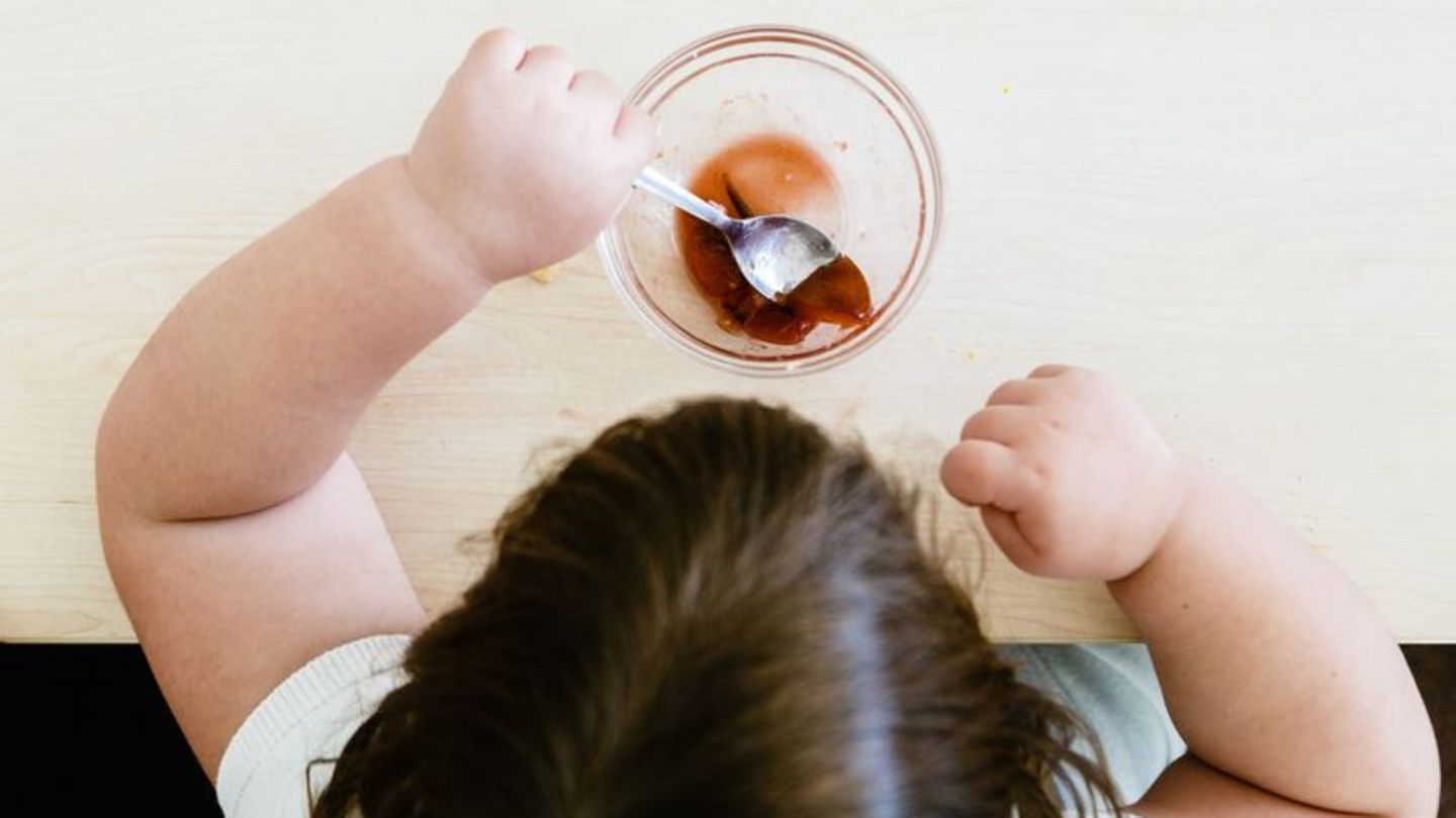 Von oben fotografiert: Kind mit dickeren Armen löffelt einen Dessert