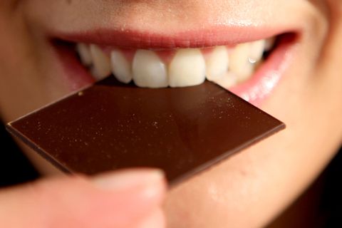 Frau isst ein Stück dunkle Schokolade