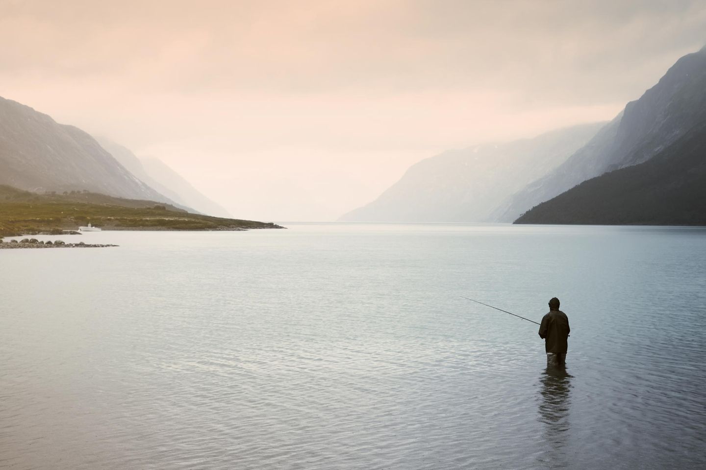 Petri Heil Eine Person steht bis zu den Knien in einem See und angelt