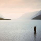 Eine Person steht bis zu den Knien in einem See und angelt