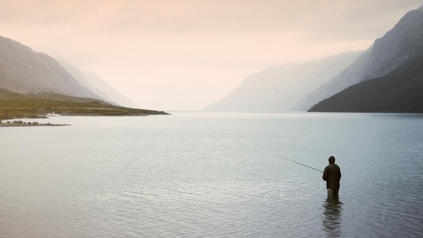 Eine Person steht bis zu den Knien in einem See und angelt