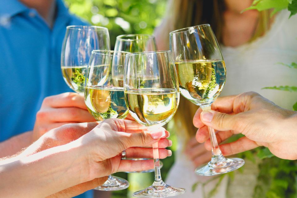 Menschen stoßen mit Weißwein an
