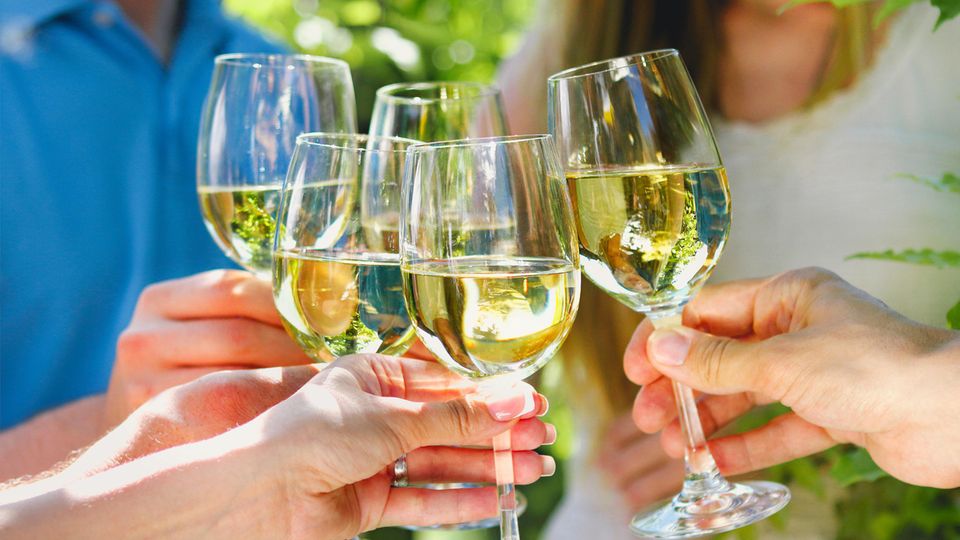 Menschen stoßen mit Weißwein an