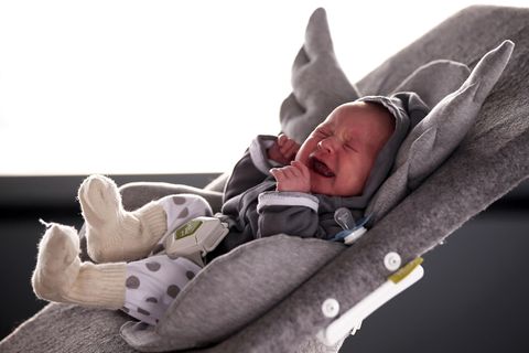 Ein Baby schreit in einer Kinderwippe.