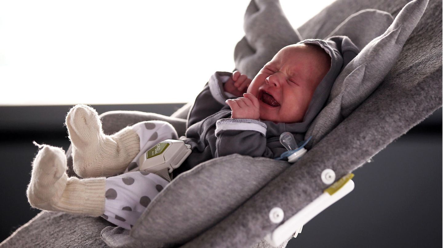 Ein Baby schreit in einer Kinderwippe.