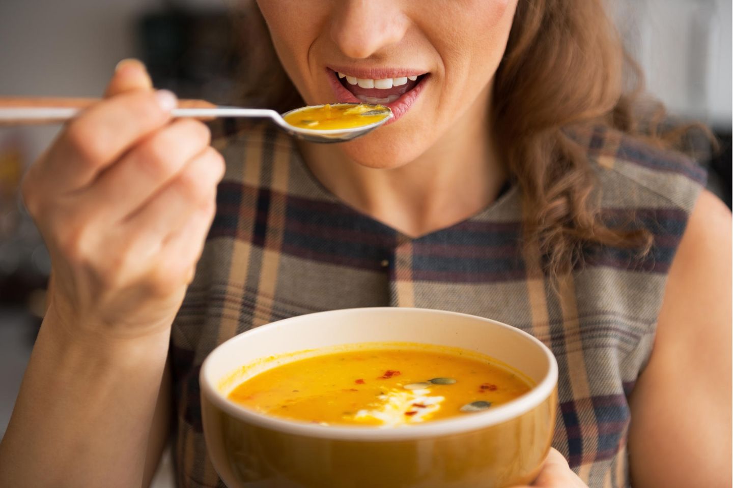 Junge Frau isst Kürbissuppe