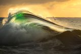 Im goldenen Licht der aufgehende Sonne ergießt sich malerisch eine Welle, während eine Möwe gen Horizont fliegt. Gergo Rugli wird Finalist in der Kategorie "Fine Art Photographer of the Year".