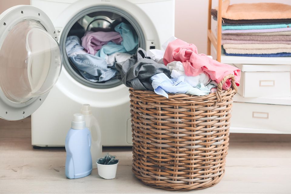 Waschmaschine und Wäschekorb mit Kleidung drin