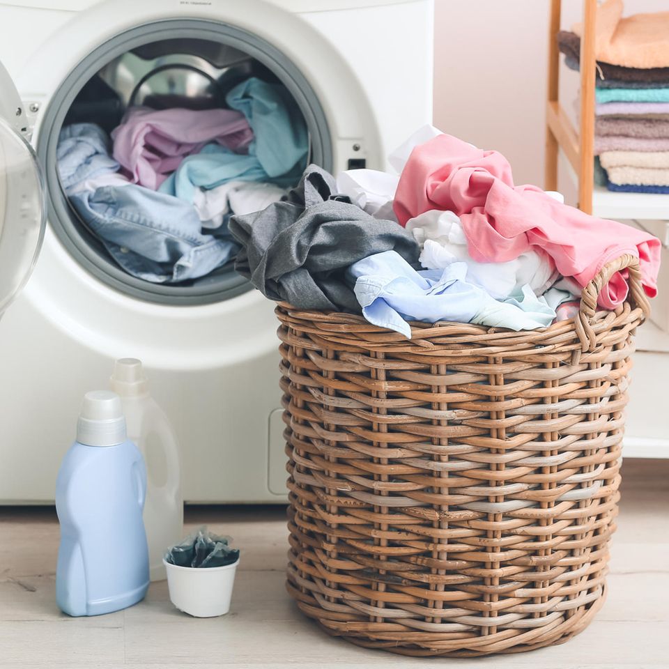 Waschmaschine und Wäschekorb mit Kleidung drin