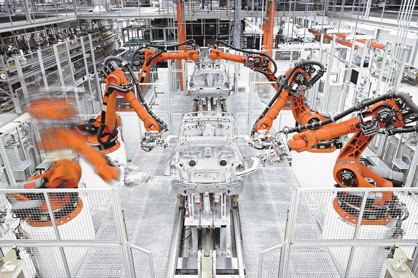Die Produktion der Zukunft? Eingezäunte Industrieroboter der KUKA AG bauen eine Automobil-Karosserie zusammen