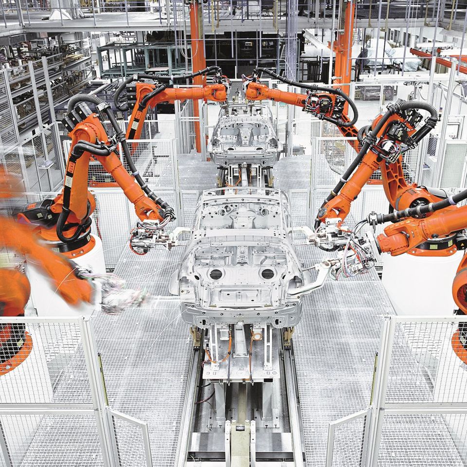 Die Produktion der Zukunft? Eingezäunte Industrieroboter der KUKA AG bauen eine Automobil-Karosserie zusammen
