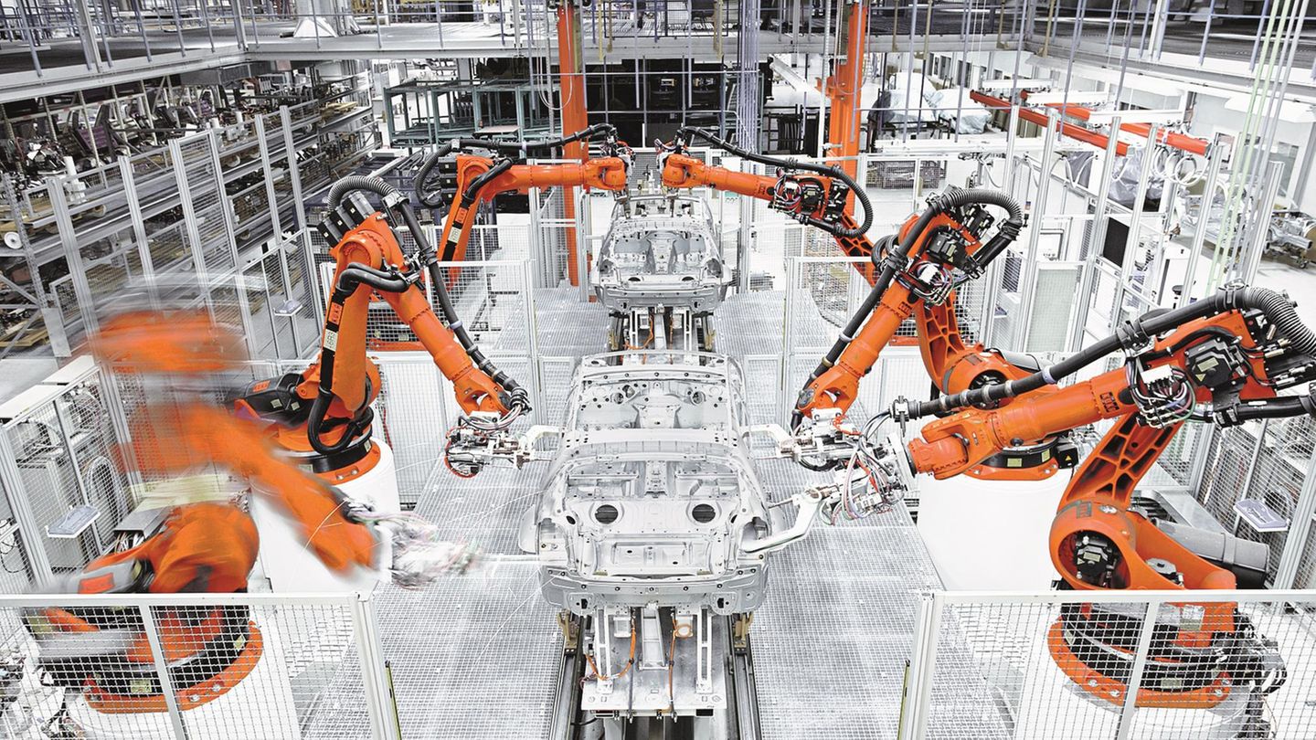 Die Produktion der Zukunft? Eingezäunte Industrieroboter der KUKA AG bauen eine Automobil-Karosserie zusammen