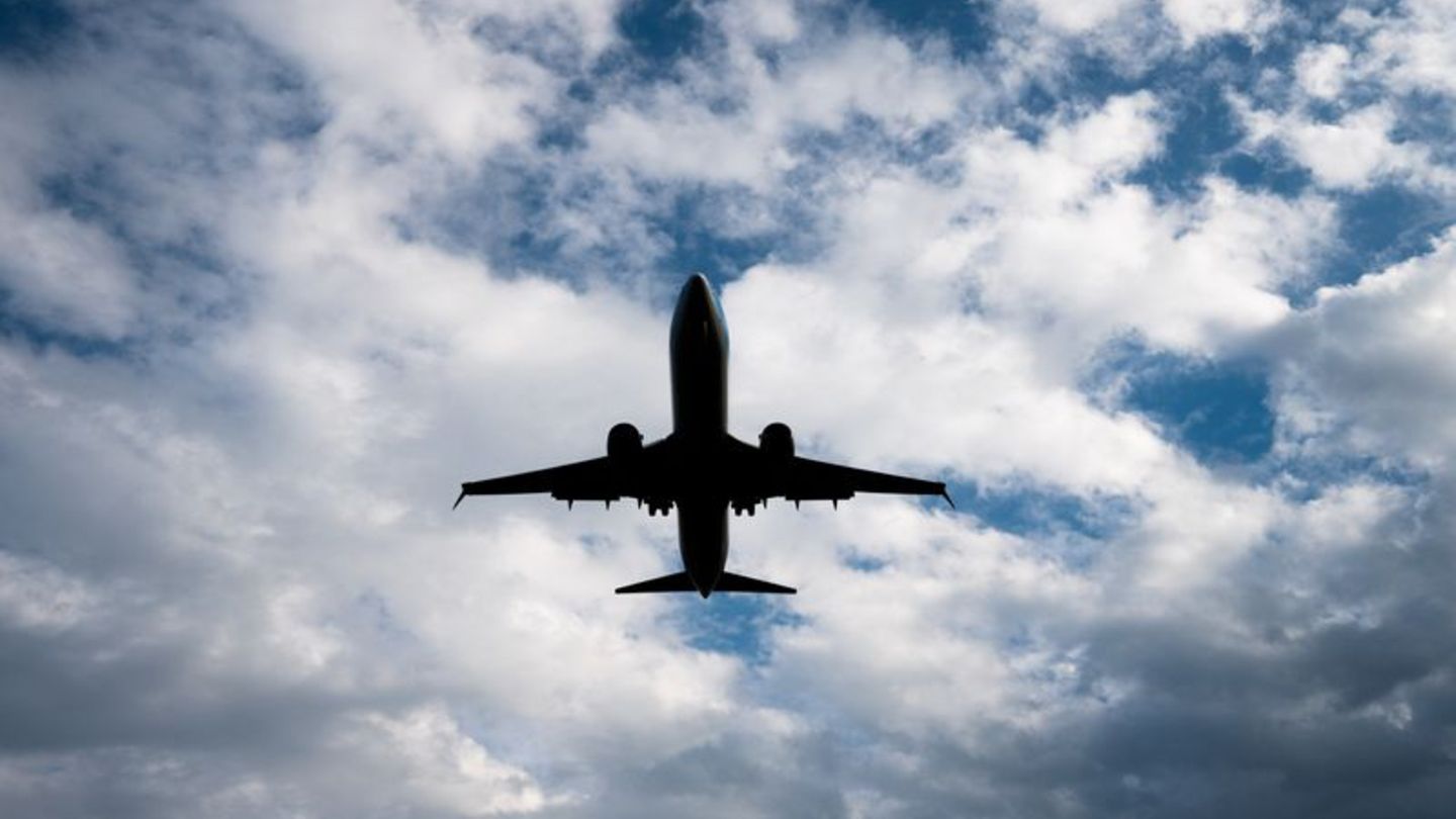 Flugzeug von unten fotografiert vor blauem Himmel mit Wolken