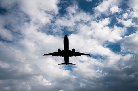Flugzeug von unten fotografiert vor blauem Himmel mit Wolken