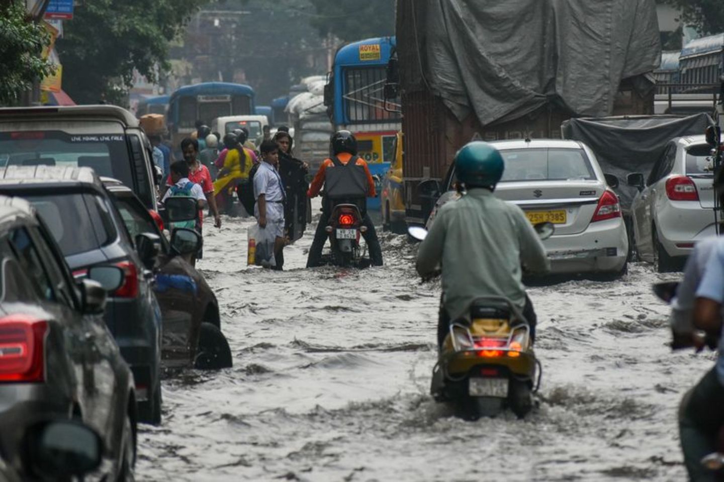 Menschen bahnen sich nach heftigen Regenfällen den Weg über eine überflutete Straße in Kalkutta