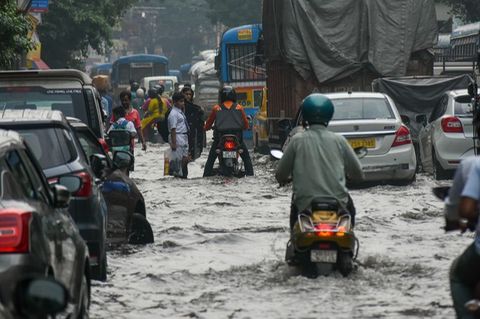 Menschen bahnen sich nach heftigen Regenfällen den Weg über eine überflutete Straße in Kalkutta