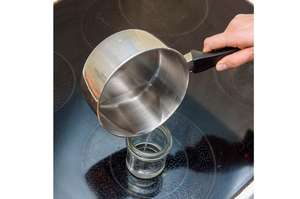 Winter-Basteln: Aus einem Kochtopf wird eine klare Flüssigkeit in ein Glas gefüllt.