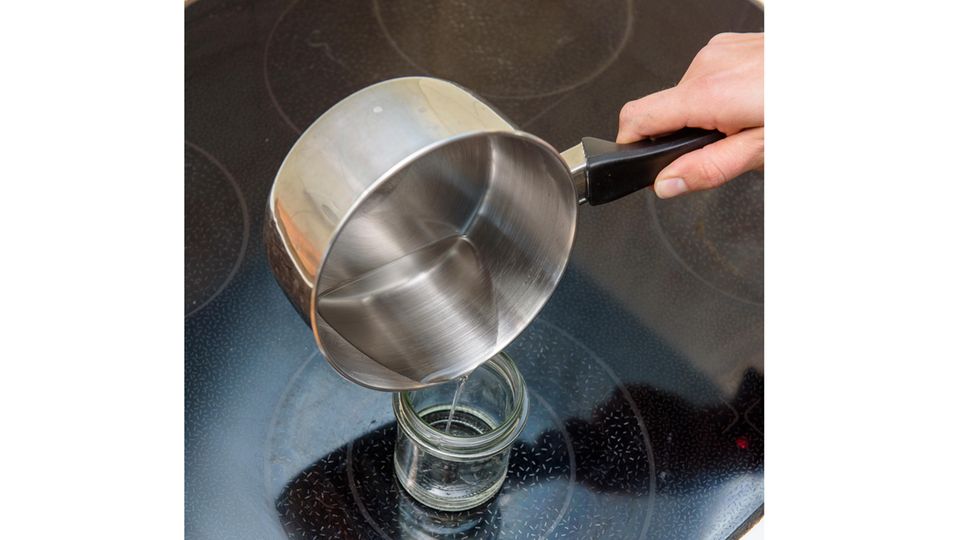Winter-Basteln: Aus einem Kochtopf wird eine klare Flüssigkeit in ein Glas gefüllt. Winter-Basteln: Aus einem Kochtopf wird eine klare Flüssigkeit in ein Glas gefüllt.