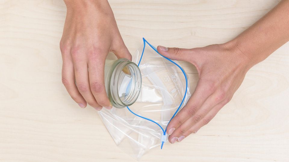 Winter-Basteln: Eine klare Flüssigkeit wird aus einem Glas in eine wiederverschließbare Plastiktüte gekippt. Winter-Basteln: Eine klare Flüssigkeit wird aus einem Glas in eine wiederverschließbare Plastiktüte gekippt.