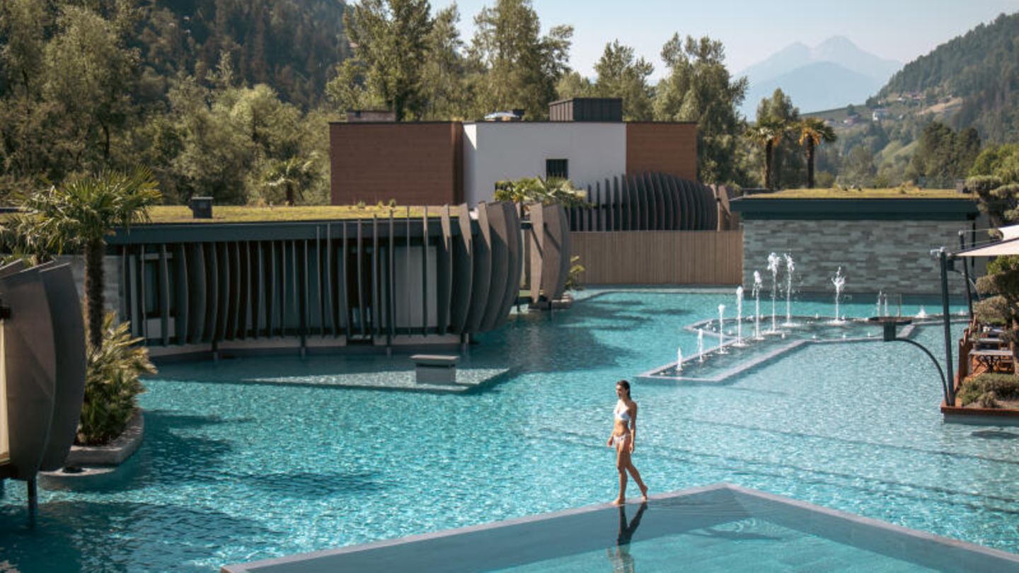 Kategorie Neu: Quellenhof See Lodge Große Poolanlage, an der eine Frau entlangläuft
