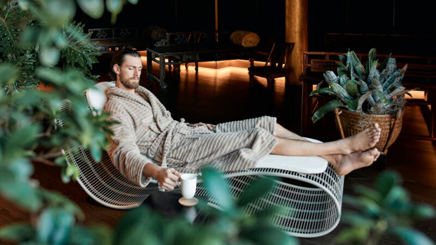 Kategorie Neu: Manner Resort in Südtirol, Italien Ein Mann liegt im Bademantel auf einer Liege und stellt seine Tasse zur Seite