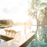 Eine Frau steht auf einem Steg, der über einen großen Naturpool ragt