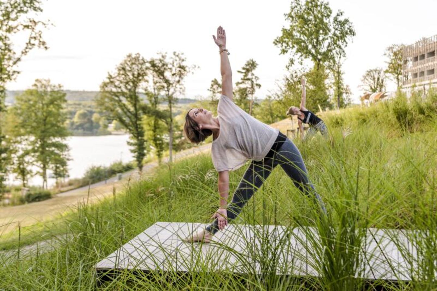 Kategorie Nachhaltig: Die Seezeitlodge im Saarland, Deutschland Zwei Frauen machen Yoga auf einer Wiese