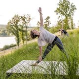 Zwei Frauen machen Yoga auf einer Wiese