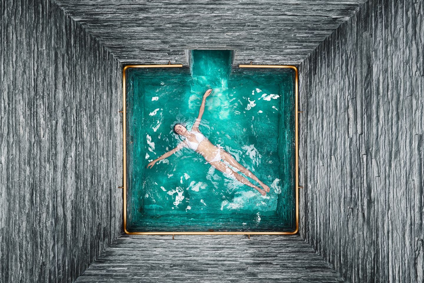 Eine Frau schwimmt an der Wasseroberfläche in einer Therme