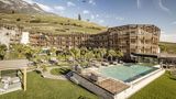 Hotelanlage aus viel Holz an einem Berg, davor ist ein großer Pool