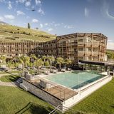 Hotelanlage aus viel Holz an einem Berg, davor ist ein großer Pool