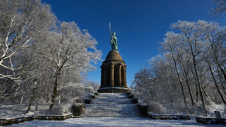 Das Hermannsdenkmal leuchtet in Detmold zwischen verschneiten Bäumen in der Sonne