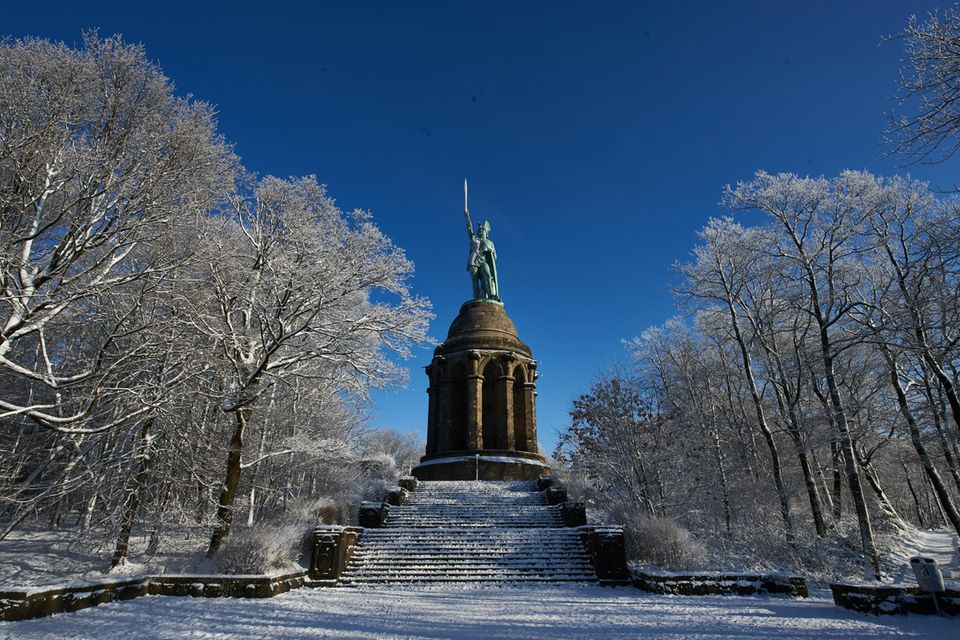 Das Hermannsdenkmal leuchtet in Detmold zwischen verschneiten Bäumen in der Sonne