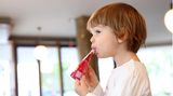 Ein zweijähriges Maedchen nuckelt an einem Quetschie
