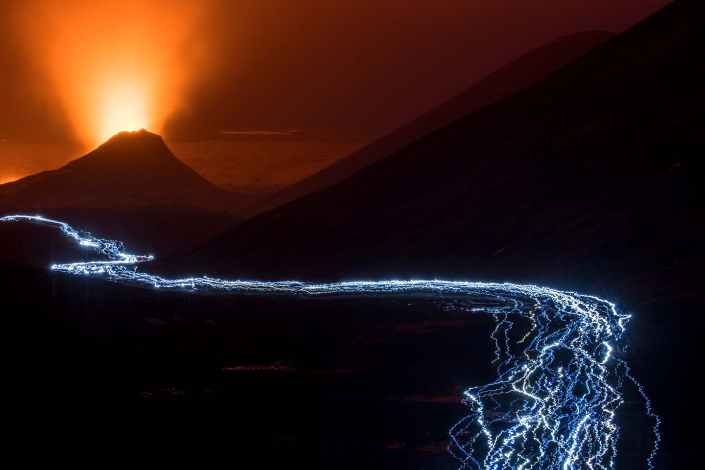Den Ausbruch des isländischen Vulkans Fagradalsfjall fotografierte Theo Bosboom. Die Leuchtspur im Vordergrund erinnert den Fotografen an einen Lavafluss. Tatsächlich bildete er durch Langzeitbelichtung die Stirn-Taschenlampen der Touristenströme ab, auf dem Weg zum Vulkan oder zurück.