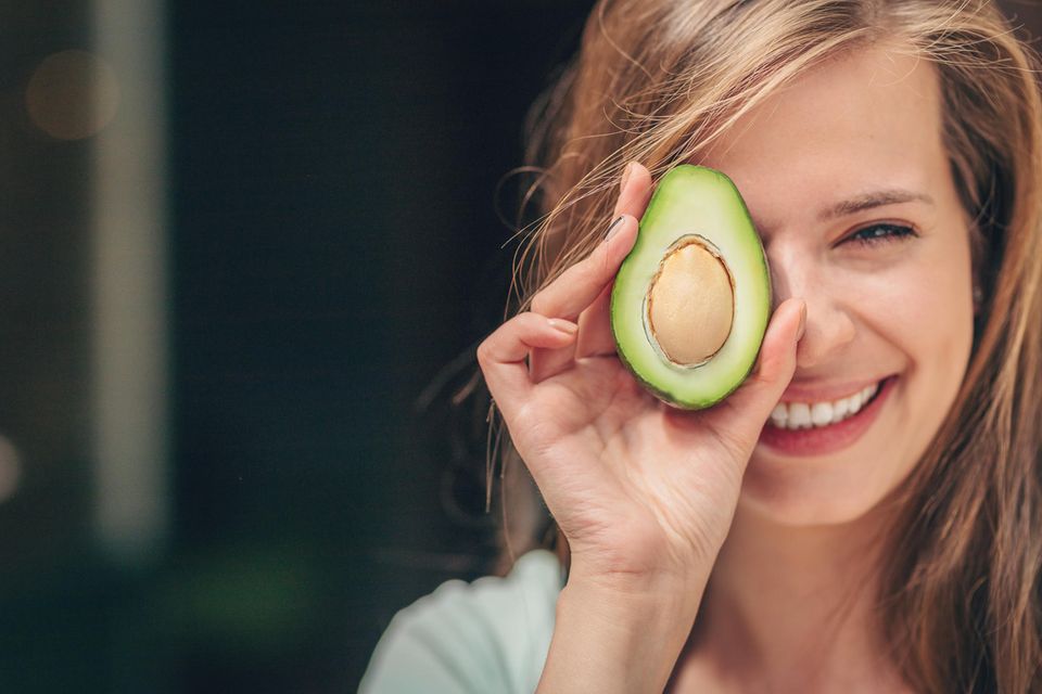 Lächelnde Frau mit einer Avocado