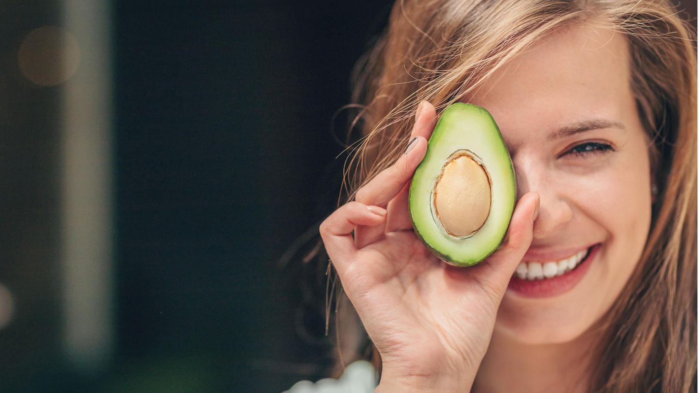 Lächelnde Frau mit einer Avocado Lächelnde Frau mit einer Avocado