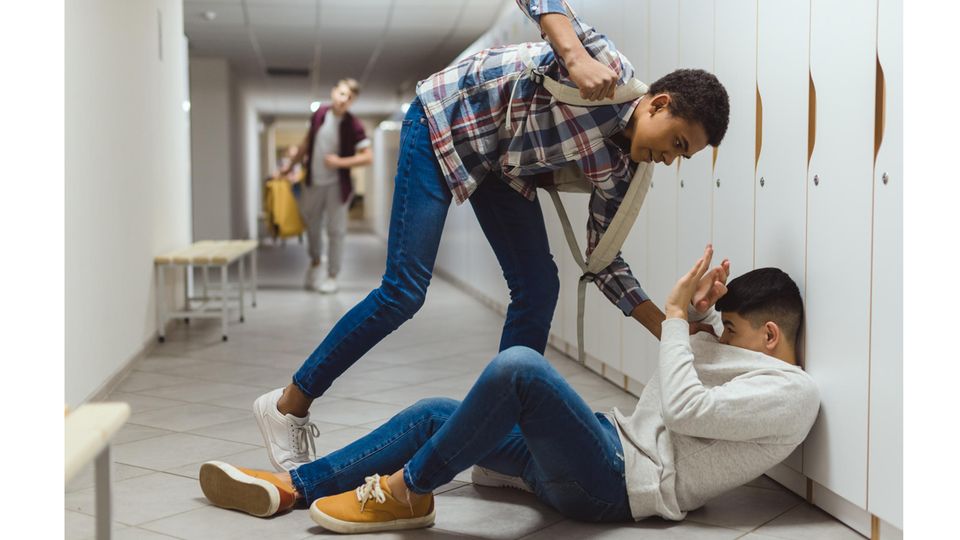 Ein Junge droht einen anderen Jungen, der am Boden liegt, zu schlagen. Ein Junge droht einen anderen Jungen, der am Boden liegt, zu schlagen.