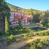 Blick über den Garten auf ein Kloster, umringt von Pflanzen