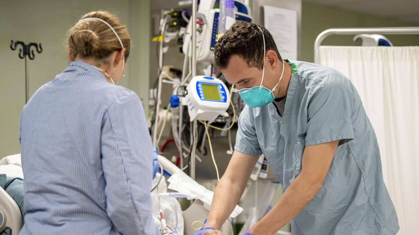 Ein Arzt und eine Ärztin behandeln eine ältere Corona-Patientin