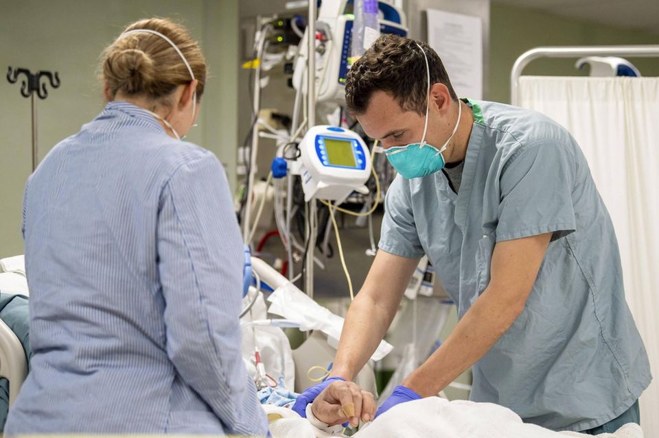 Ein Arzt und eine Ärztin behandeln eine ältere Corona-Patientin