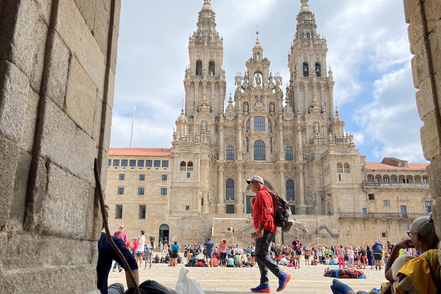 Blick durch eine Einfahrt auf den Obradoiro-Platz in Santiago de Compostela voller Pilger