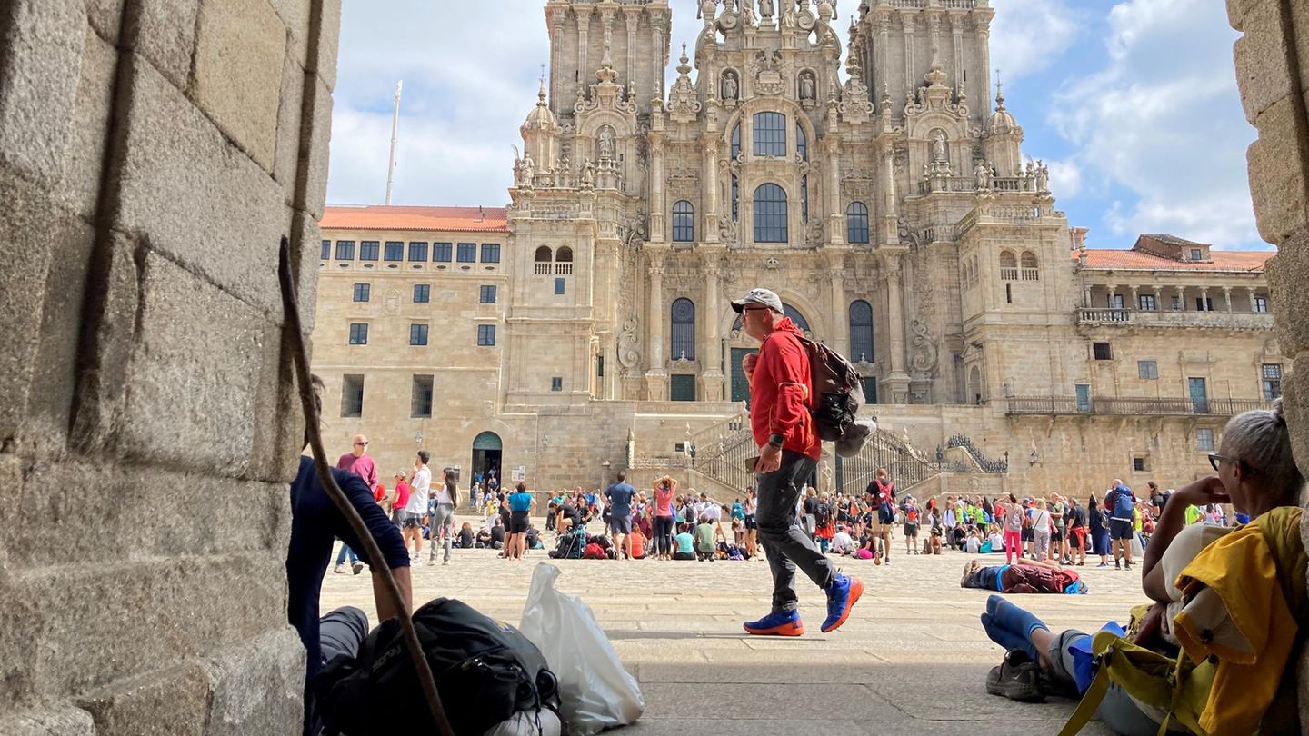 Blick durch eine Einfahrt auf den Obradoiro-Platz in Santiago de Compostela voller Pilger