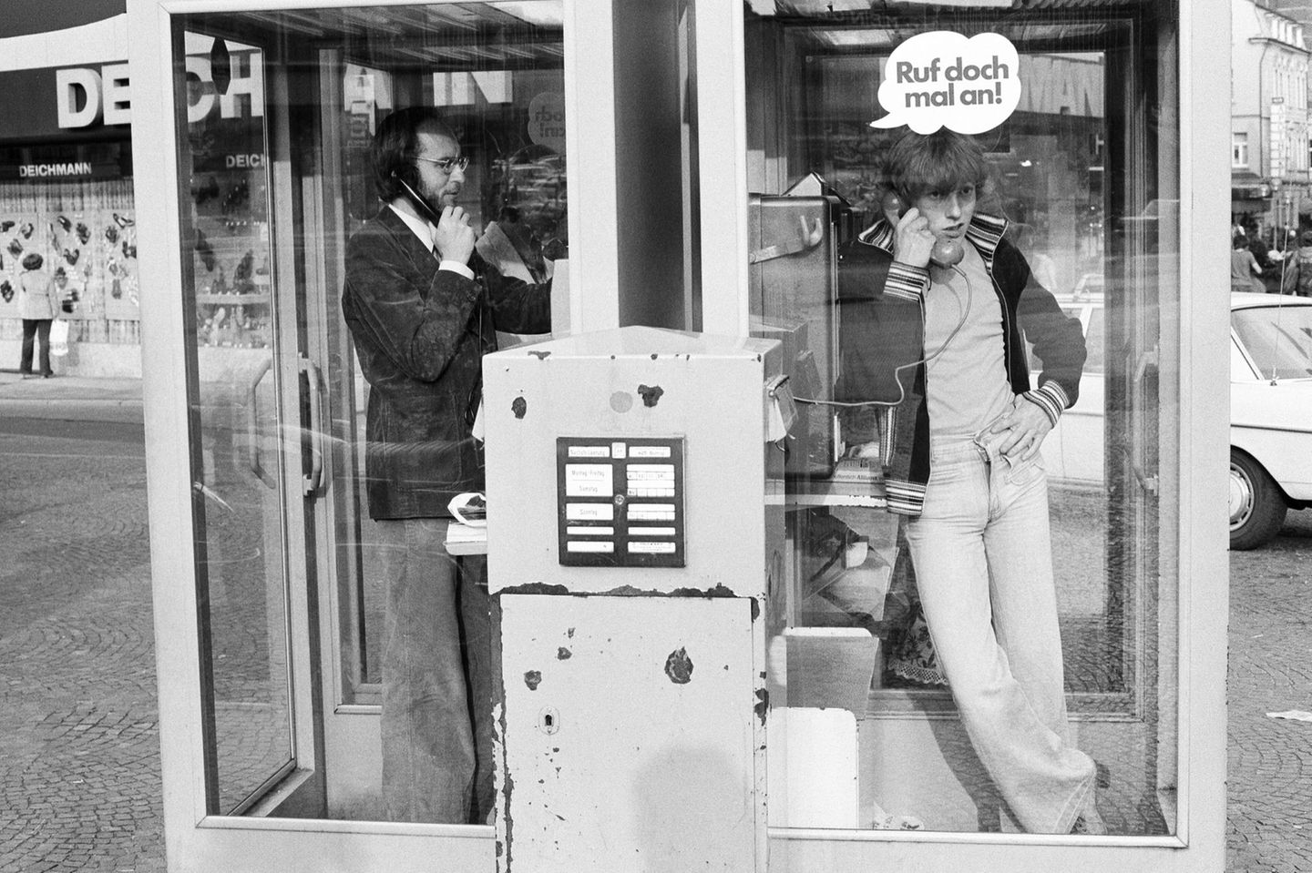 Zwei Männer telefonieren in zwei Telefonzellen