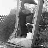 Frau telefoniert in demolierter Telefonzelle, 1973