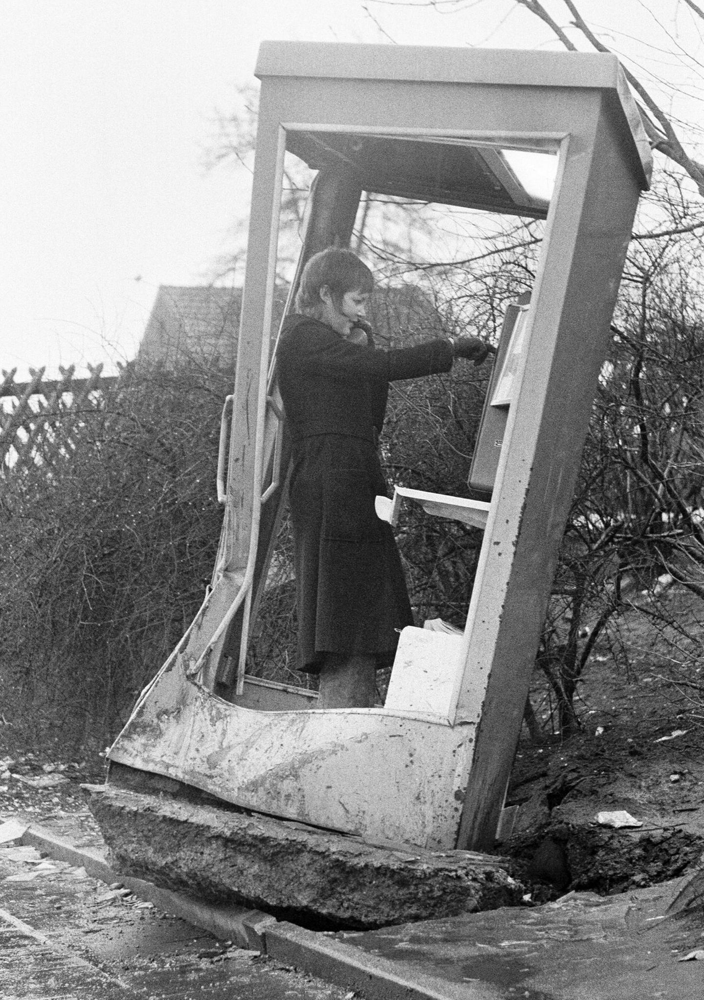 Frau telefoniert in demolierter Telefonzelle, 1973