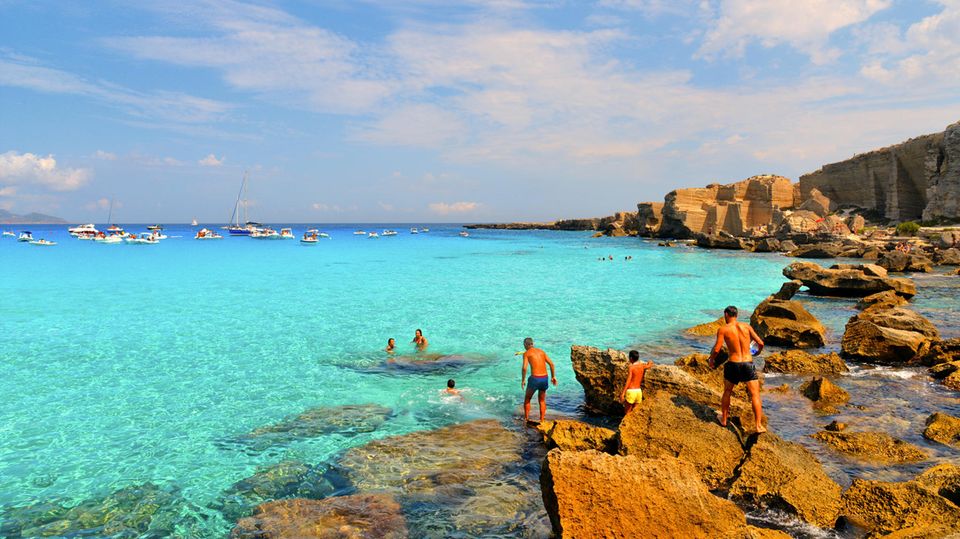 Menschen auf den Felsen und im Wasser an der Cala Rossa, Favignana
